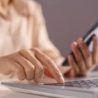 Pessoa utilizando um notebook e um celular para realizar atividades online, representando o uso de ferramentas digitais para vendas e pagamentos.